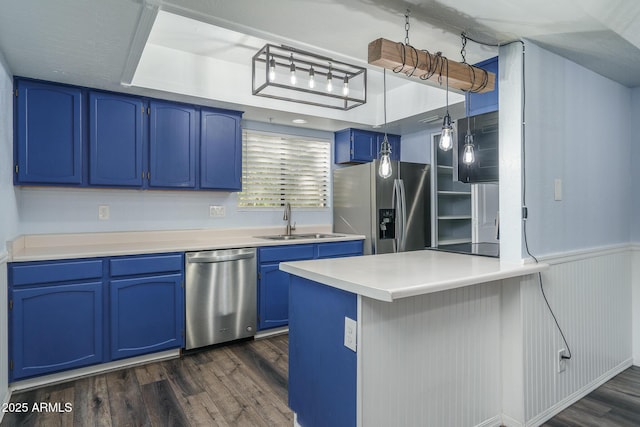 kitchen with kitchen peninsula, appliances with stainless steel finishes, dark wood-type flooring, sink, and blue cabinetry