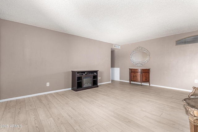 unfurnished living room featuring light hardwood / wood-style floors and a textured ceiling