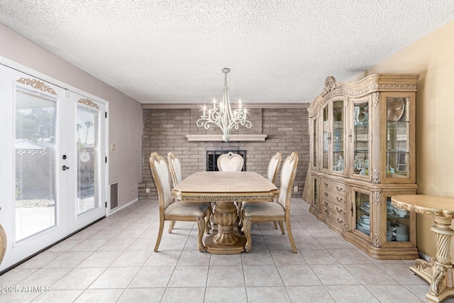 dining room with french doors, an inviting chandelier, a textured ceiling, light tile patterned floors, and brick wall