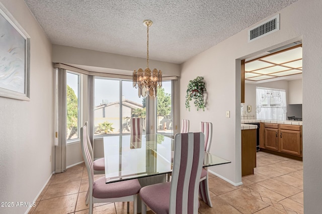 tiled dining room featuring a healthy amount of sunlight, a textured ceiling, and an inviting chandelier