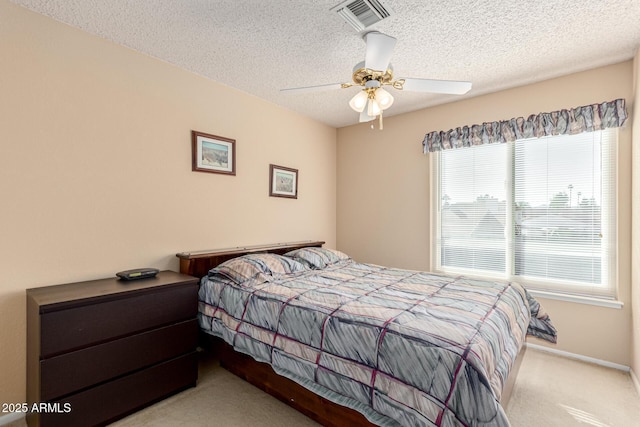 bedroom featuring ceiling fan, light carpet, and a textured ceiling