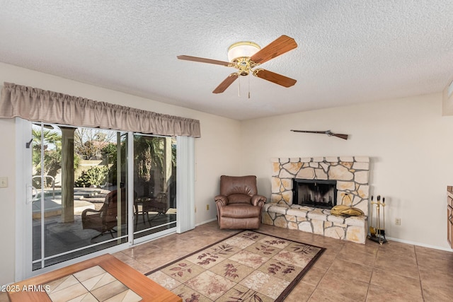 tiled living room featuring ceiling fan, a fireplace, and a textured ceiling