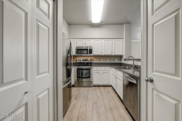 20100 N 78th Pl Unit 2019, Scottsdale, AZ 85255 - kitchen featuring appliances with stainless steel finishes, light wood-style floors, white cabinets, dark countertops, and a textured ceiling