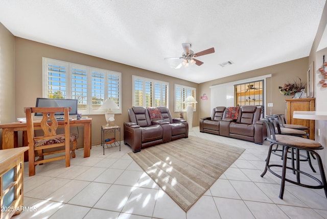 living room with ceiling fan, light tile patterned floors, and a textured ceiling