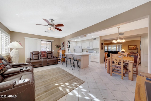 living room featuring ceiling fan with notable chandelier, light tile patterned floors, a textured ceiling, and a wealth of natural light