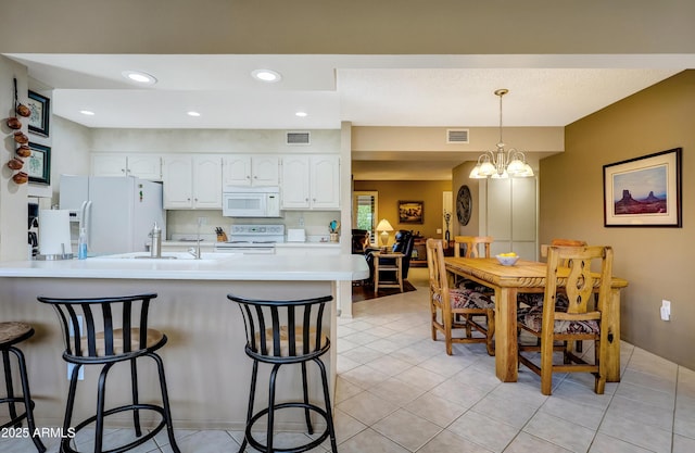 kitchen with a kitchen bar, kitchen peninsula, white cabinets, and white appliances