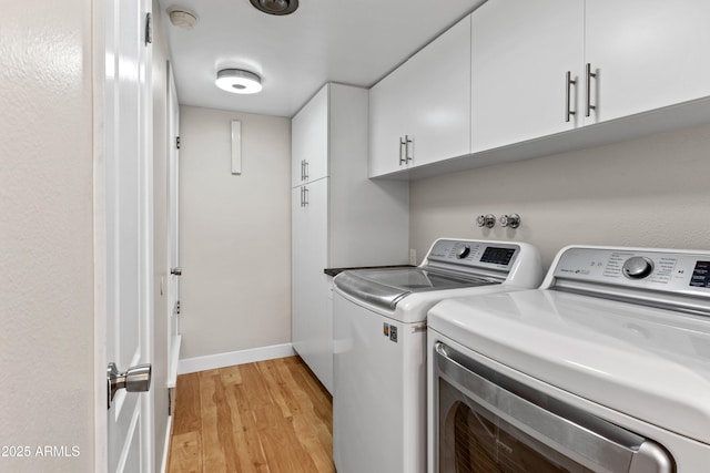 washroom with cabinets, light hardwood / wood-style floors, and washing machine and dryer