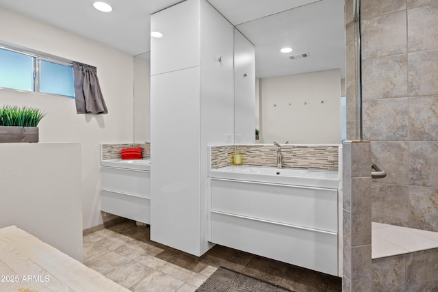 bathroom featuring vanity, decorative backsplash, and a shower