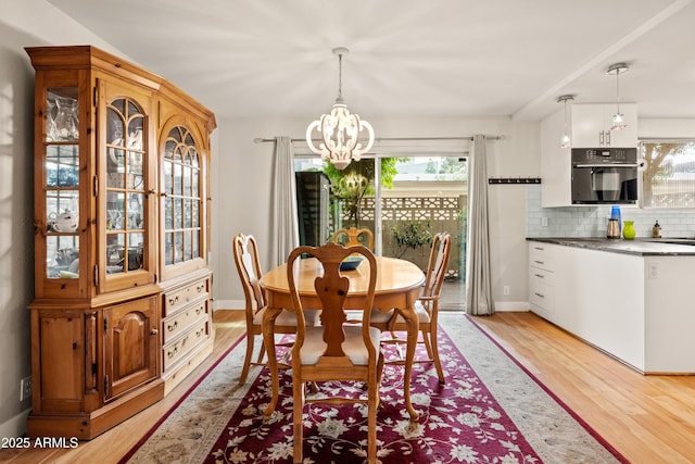 dining room with a notable chandelier, light hardwood / wood-style floors, and a healthy amount of sunlight