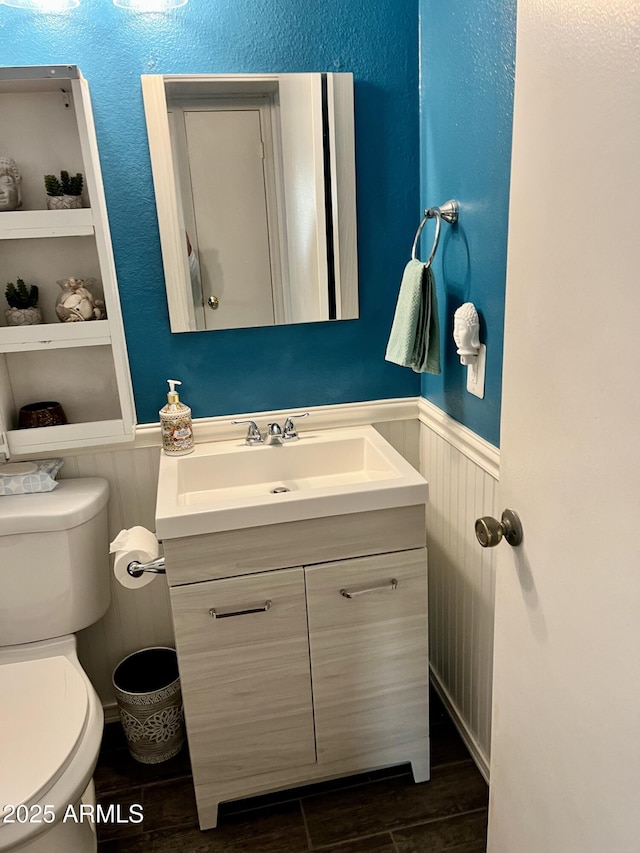 bathroom featuring hardwood / wood-style flooring, built in shelves, toilet, and vanity