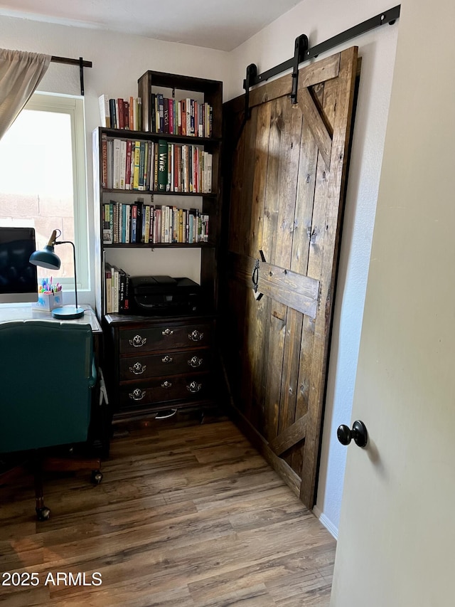 office featuring a barn door and wood-type flooring