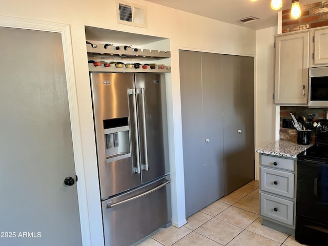 kitchen featuring light stone countertops, black range with electric cooktop, high end refrigerator, backsplash, and light tile patterned floors