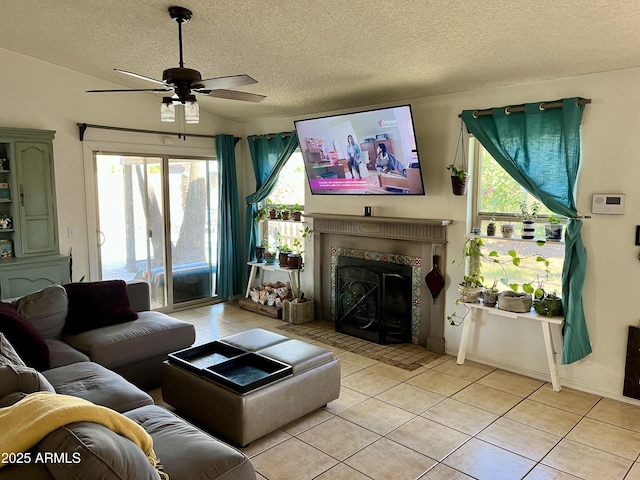 living room featuring a fireplace, light tile patterned floors, a textured ceiling, and ceiling fan