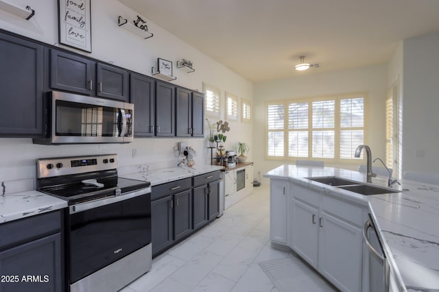 kitchen featuring light stone counters, appliances with stainless steel finishes, and sink