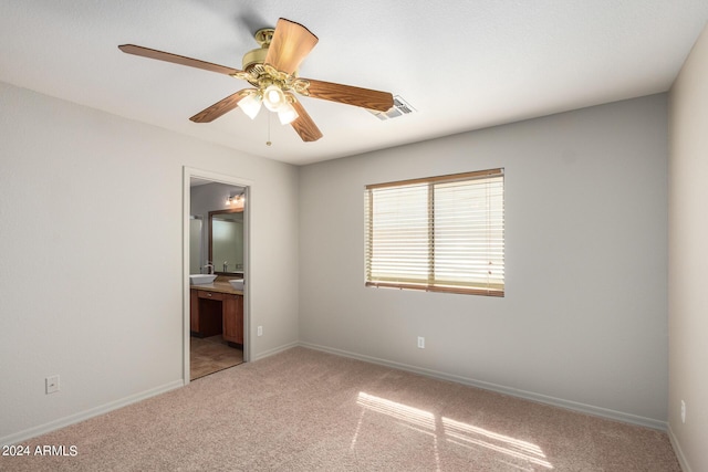 unfurnished bedroom featuring ceiling fan, light colored carpet, and ensuite bath