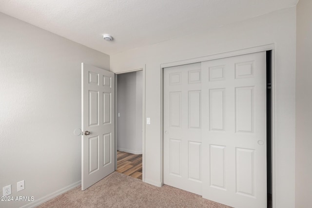 unfurnished bedroom featuring light colored carpet, a closet, and a textured ceiling