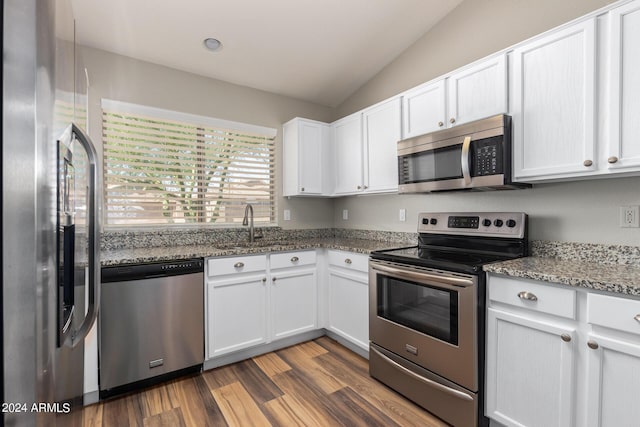 kitchen featuring lofted ceiling, sink, white cabinetry, dark stone countertops, and stainless steel appliances