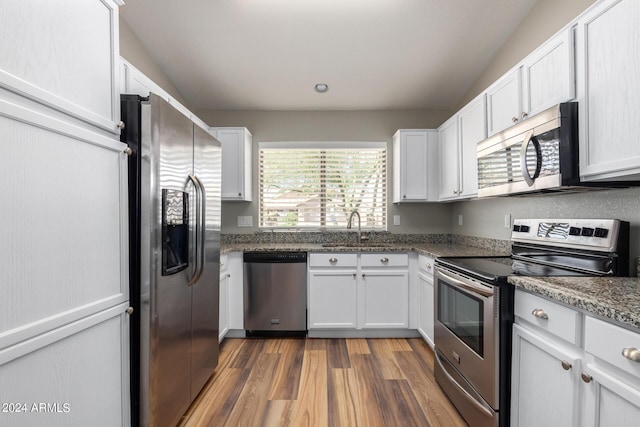 kitchen featuring white cabinetry, sink, dark stone counters, and appliances with stainless steel finishes