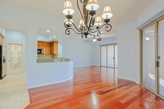 interior space with stainless steel refrigerator with ice dispenser, sink, hanging light fixtures, light hardwood / wood-style flooring, and backsplash