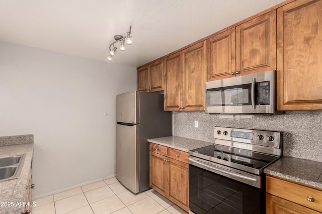 11260 N 92nd St Unit 2102, Scottsdale, AZ 85260 - kitchen featuring appliances with stainless steel finishes, brown cabinetry, decorative backsplash, and light tile patterned floors