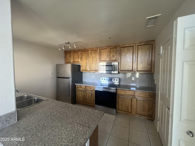 11260 N 92nd St Unit 2102, Scottsdale, AZ 85260 - kitchen with stainless steel appliances, brown cabinets, decorative backsplash, light tile patterned flooring, and tile counters