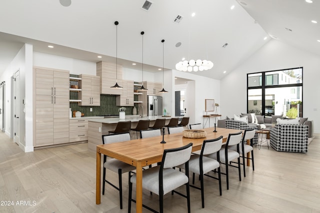 dining area with light hardwood / wood-style flooring, high vaulted ceiling, and sink