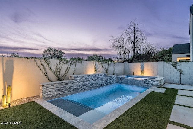 pool at dusk with an in ground hot tub