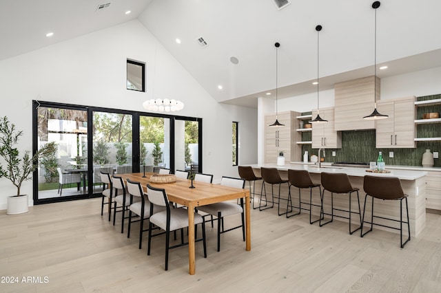 dining area with light hardwood / wood-style flooring, high vaulted ceiling, and sink