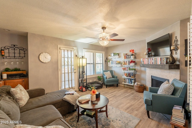 8787 E Mountain View Rd Unit 1110, Scottsdale, AZ 85258 - living area featuring ceiling fan, wood finished floors, a fireplace, and a textured ceiling