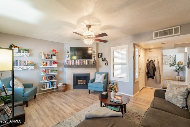 8787 E Mountain View Rd Unit 1110, Scottsdale, AZ 85258 - living room with a ceiling fan, a tiled fireplace, and wood finished floors