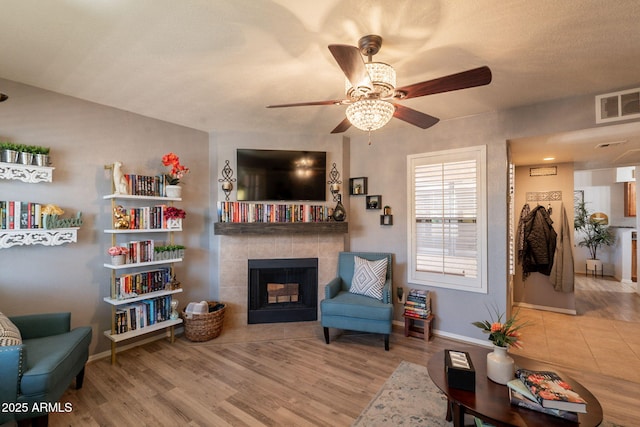 8787 E Mountain View Rd Unit 1110, Scottsdale, AZ 85258 - living room with a ceiling fan, a tiled fireplace, and wood finished floors