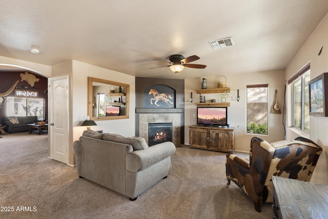 living room featuring ceiling fan, carpet flooring, plenty of natural light, and a tile fireplace