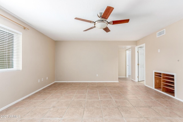 spare room with light tile patterned floors, ceiling fan, visible vents, and baseboards