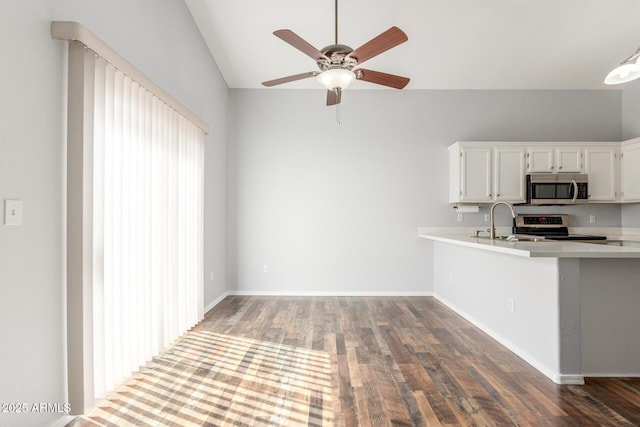 kitchen with appliances with stainless steel finishes, white cabinets, light countertops, and wood finished floors