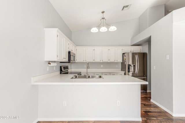 kitchen with stainless steel appliances, light countertops, visible vents, a sink, and a peninsula