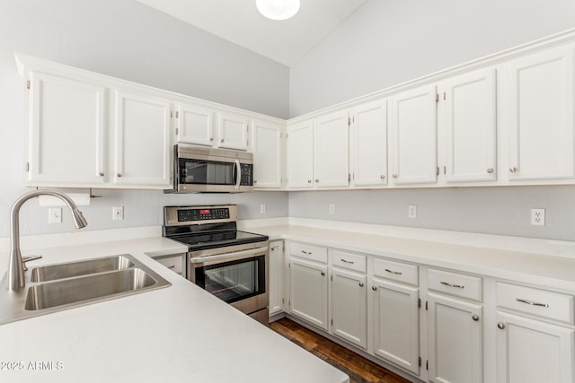 kitchen featuring lofted ceiling, appliances with stainless steel finishes, white cabinets, and a sink