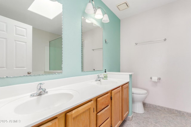 bathroom with a skylight, a sink, toilet, and double vanity