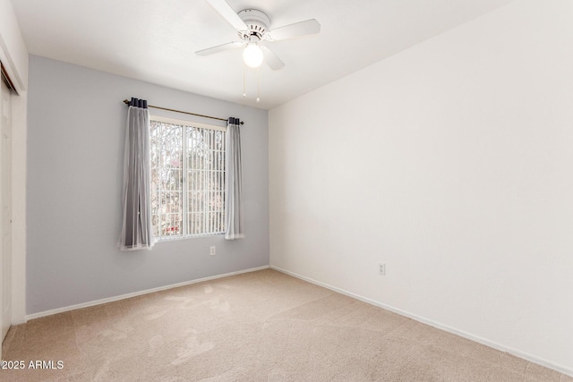 carpeted empty room featuring a ceiling fan and baseboards