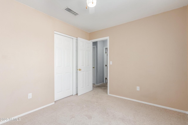 unfurnished bedroom featuring light carpet, baseboards, visible vents, and a closet