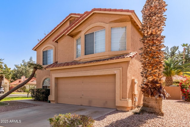 view of front of house with concrete driveway, a tile roof, an attached garage, and stucco siding