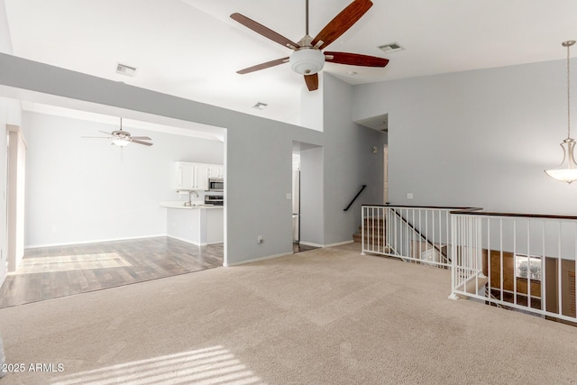 empty room with high vaulted ceiling, ceiling fan, visible vents, and carpet flooring