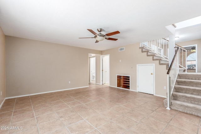 unfurnished living room featuring a ceiling fan, light tile patterned floors, baseboards, and stairs