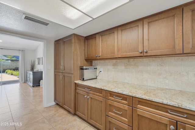 kitchen featuring visible vents, brown cabinetry, and decorative backsplash