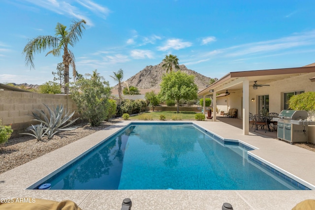 view of swimming pool featuring a mountain view, ceiling fan, a fenced backyard, grilling area, and a patio
