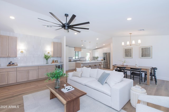 living area featuring a chandelier, lofted ceiling, light wood finished floors, a ceiling fan, and recessed lighting