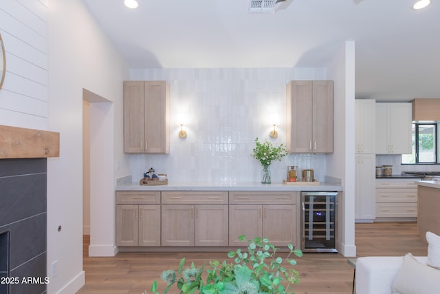 kitchen with wine cooler, decorative backsplash, light wood-style flooring, recessed lighting, and light countertops