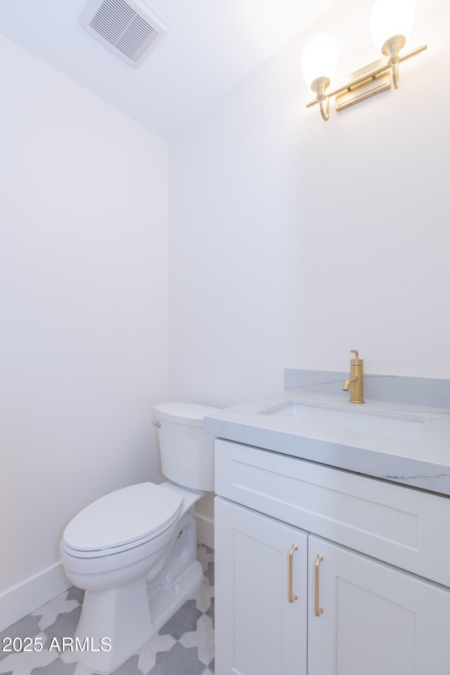 bathroom featuring vanity, toilet, baseboards, and tile patterned floors