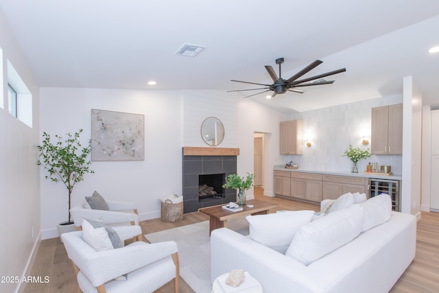 living area with wine cooler, ceiling fan, light wood-type flooring, vaulted ceiling, and baseboards