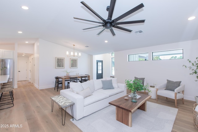 living room with lofted ceiling, recessed lighting, light wood-style floors, a chandelier, and baseboards
