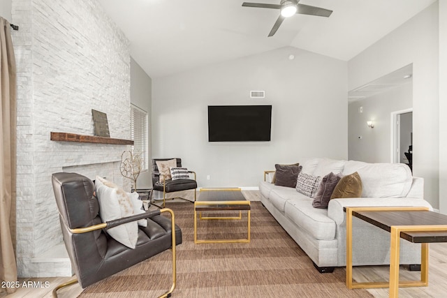 living room featuring vaulted ceiling, wood-type flooring, ceiling fan, and a fireplace